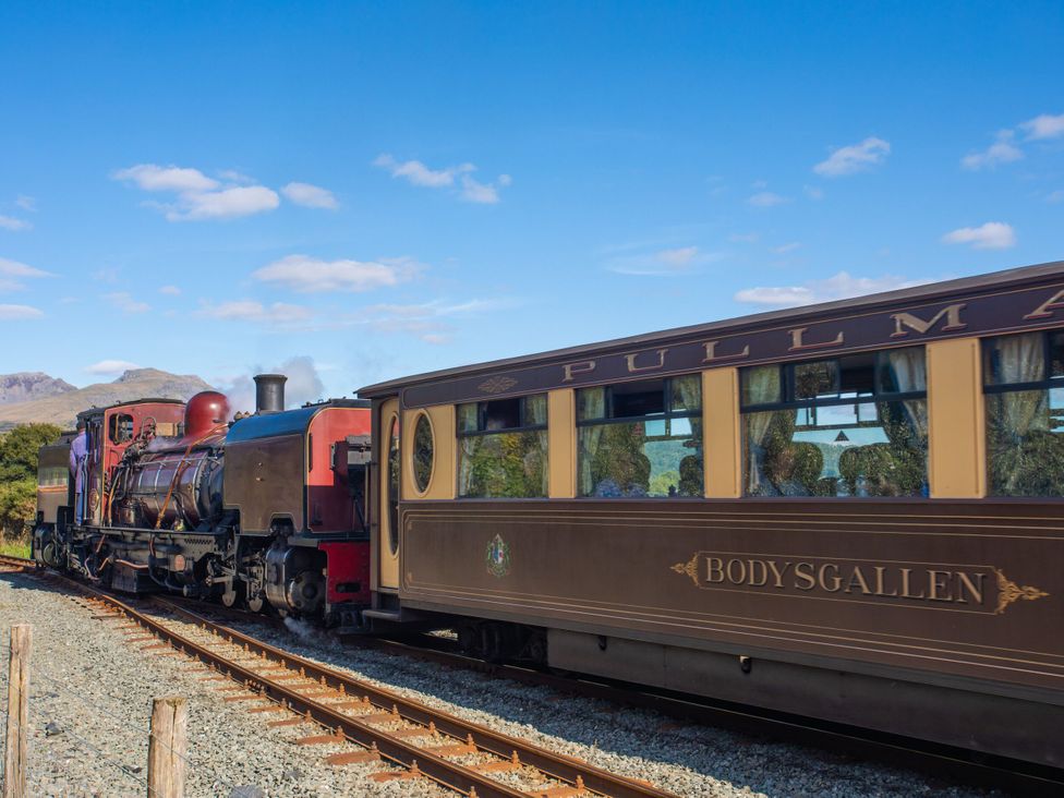 A steam locomotive and passenger carriage on train tracks in a scenic area at Maritime Mews, 6 The Oakleys, Porthmadog
