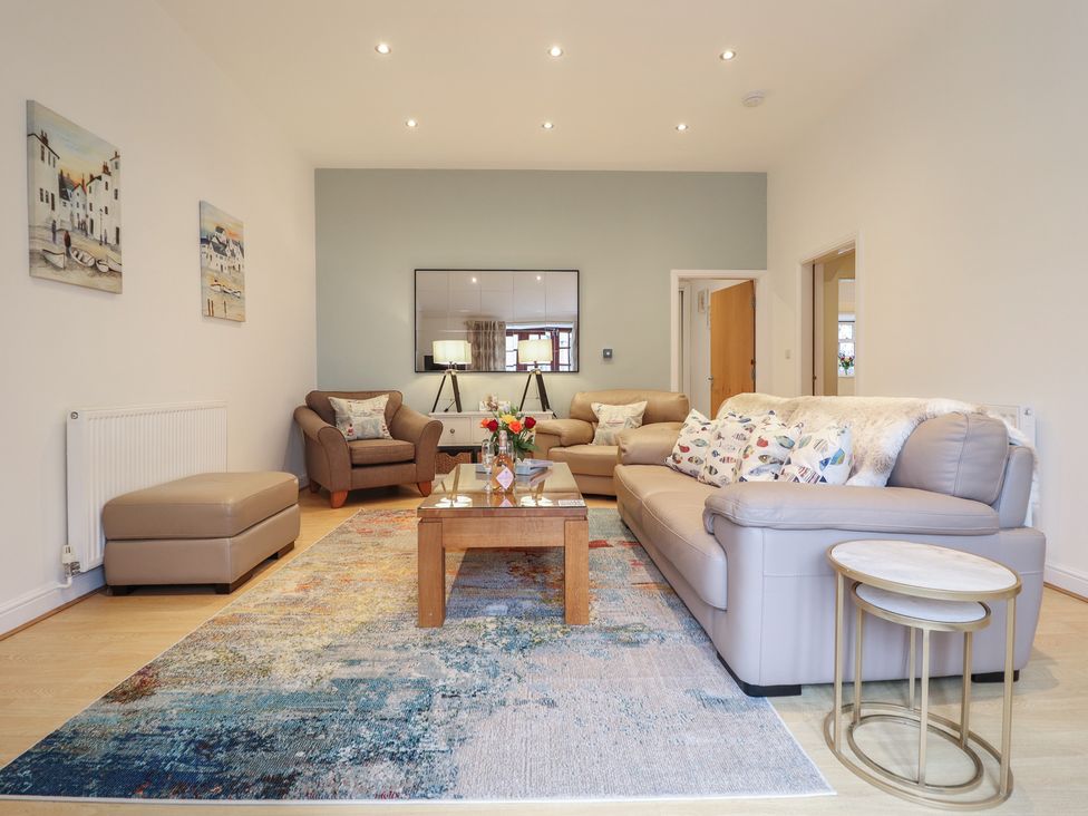 A living room with a sofa, armchair, and coffee table at Maritime Mews, 6 The Oakleys, Porthmadog
