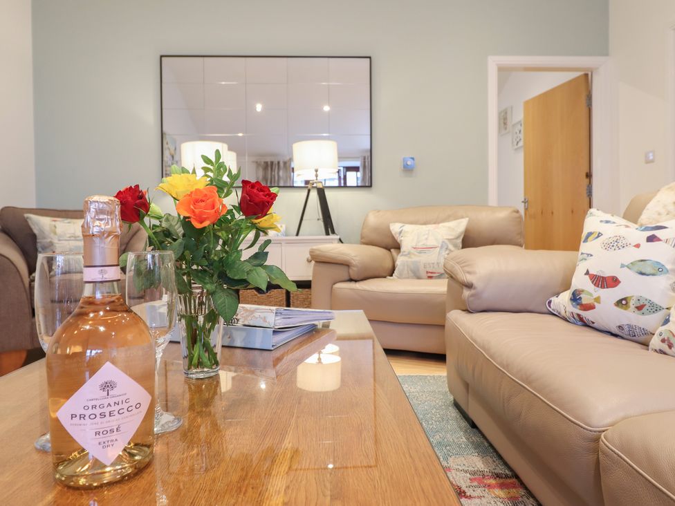 A living room with a coffee table and floral arrangement at Maritime Mews, 6 The Oakleys, Porthmadog
