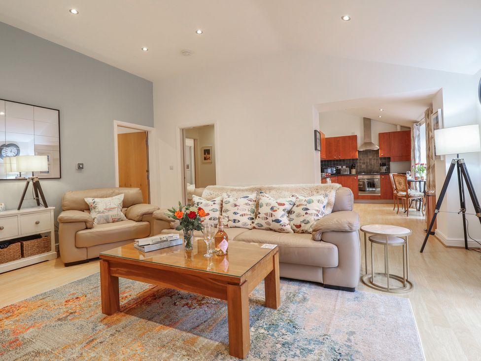 A living room with a sofa, coffee table and view of the kitchen at Maritime Mews, 6 The Oakleys, Porthmadog
