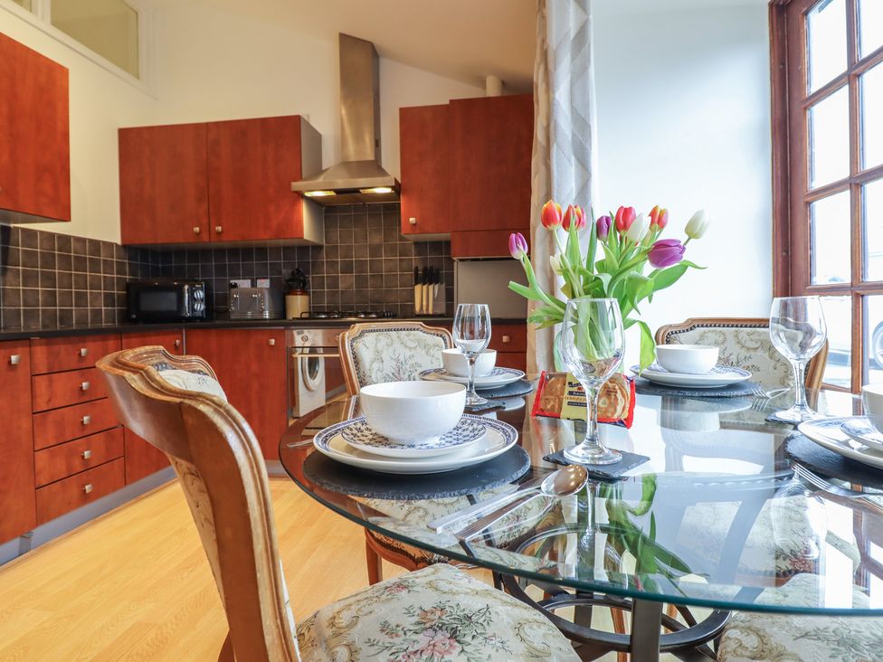 A kitchen with wooden cabinets and dining area at Maritime Mews, 6 The Oakleys, Porthmadog