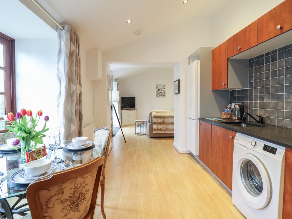 A kitchen area with a dining table and washing machine at Maritime Mews, 6 The Oakleys in Porthmadog