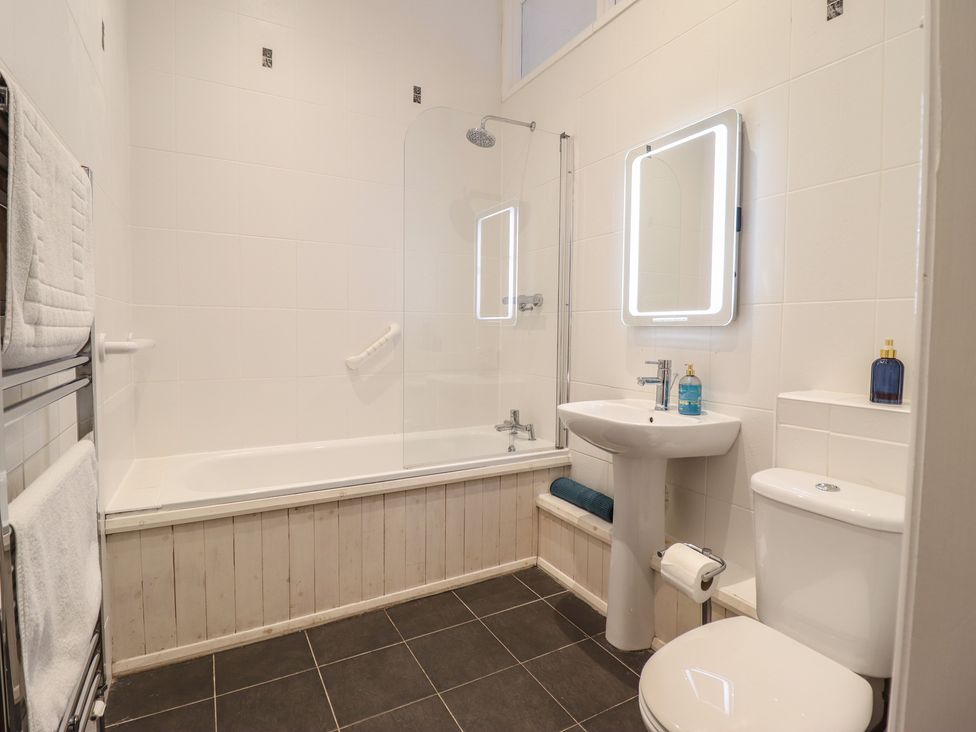 A bathroom with a shower over a bathtub and a wash basin at Maritime Mews, 6 The Oakleys, Porthmadog