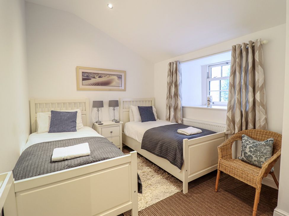 A bedroom with two beds and a nightstand at Maritime Mews, 6 The Oakleys in Porthmadog