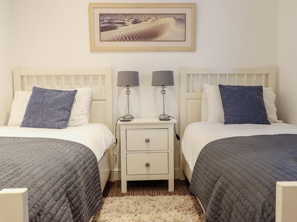 A bedroom with two beds and a nightstand at Maritime Mews, 6 The Oakleys in Porthmadog