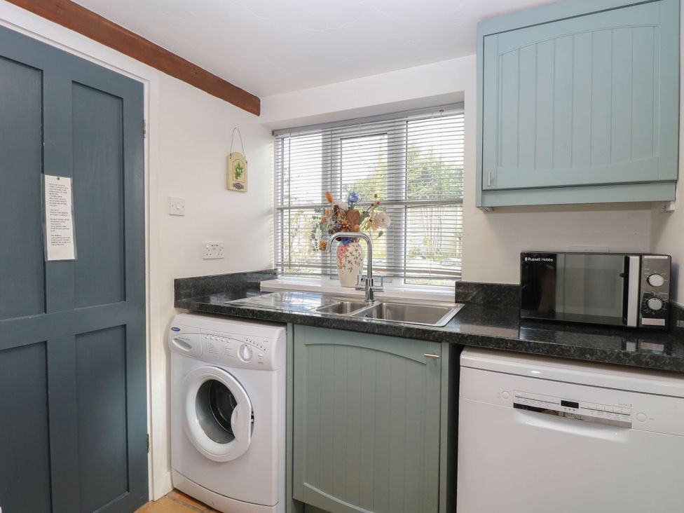 A kitchen with a washing machine, sink, microwave and dishwasher at Sleepeezy in Little Snoring