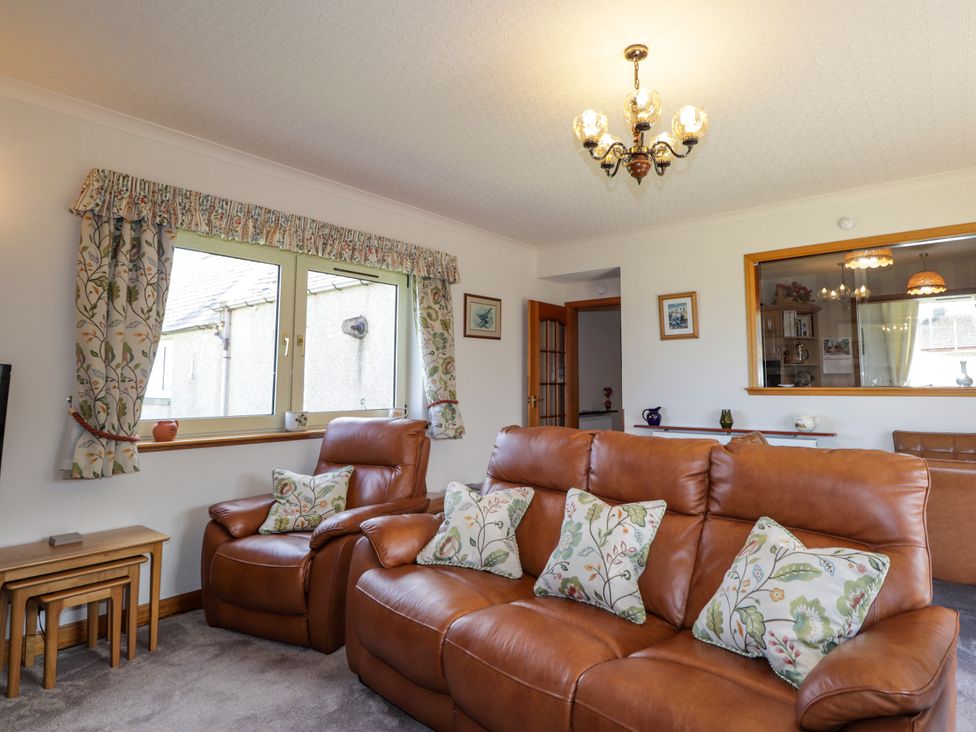 A living room with a leather sofa and window at Braehead Croft Portessie near Buckie