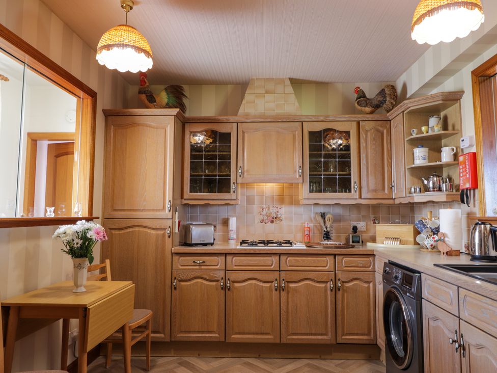 A kitchen with wooden cabinets and appliances at Braehead Croft in Portessie near Buckie