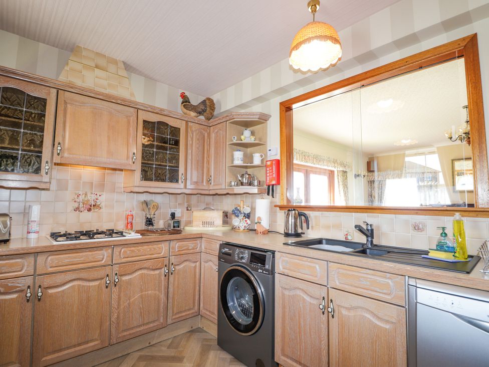 A kitchen with cabinets, a sink, washing machine, and stove at Braehead Croft in Portessie near Buckie