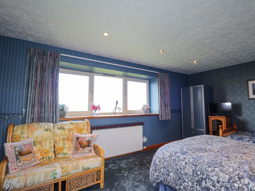 A bedroom with a bed, sofa, and window at Braehead Croft in Portessie near Buckie
