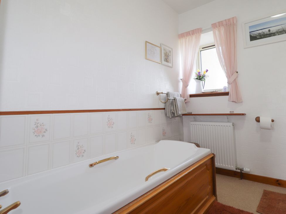 A bathroom with a bathtub and towel rack at Braehead Croft in Portessie near Buckie