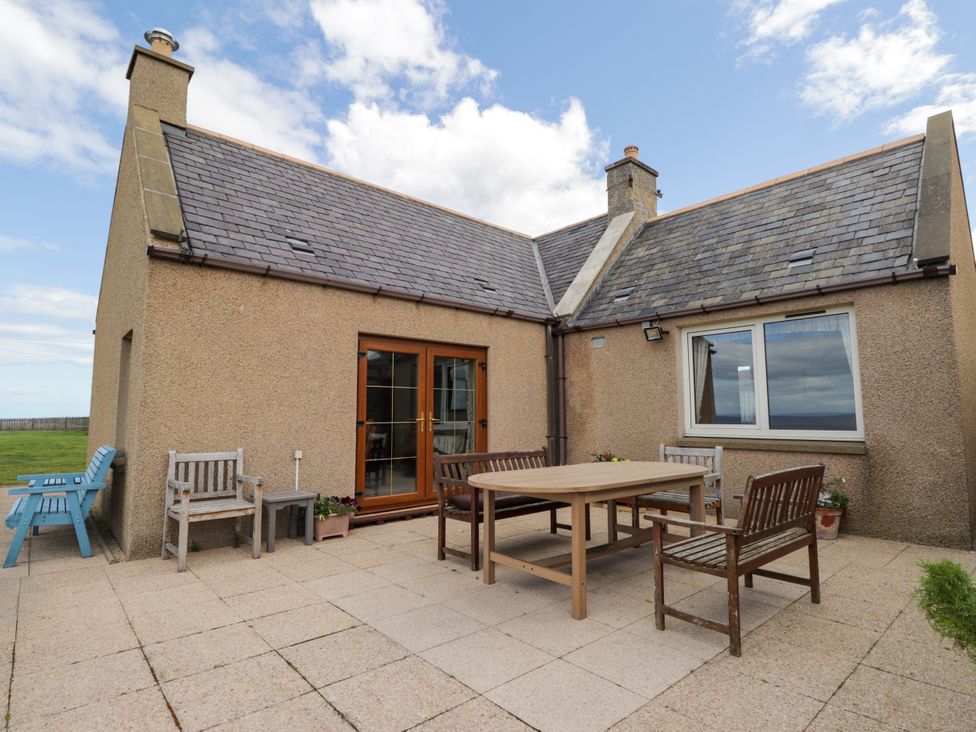An outdoor patio with a table and chairs at Braehead Croft in Portessie near Buckie