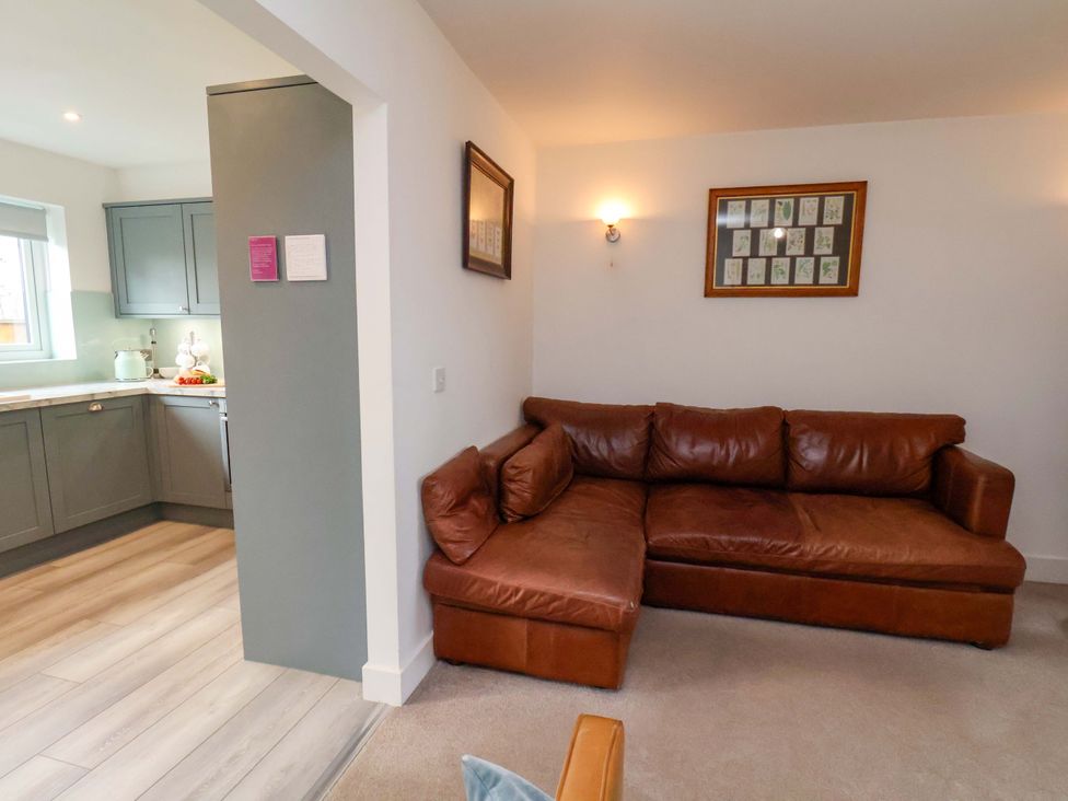 A living room with a sofa and kitchen area at Berry Banks Cottage in Whitby