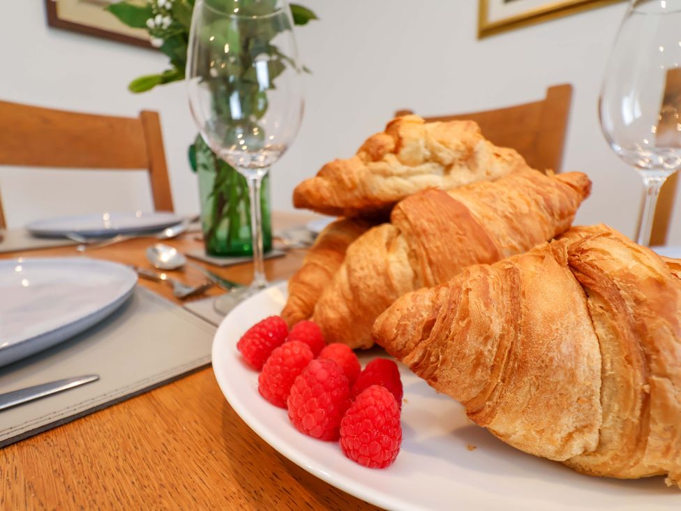 A plate with croissants and raspberries on a dining table at Berry Banks Cottage in Whitby