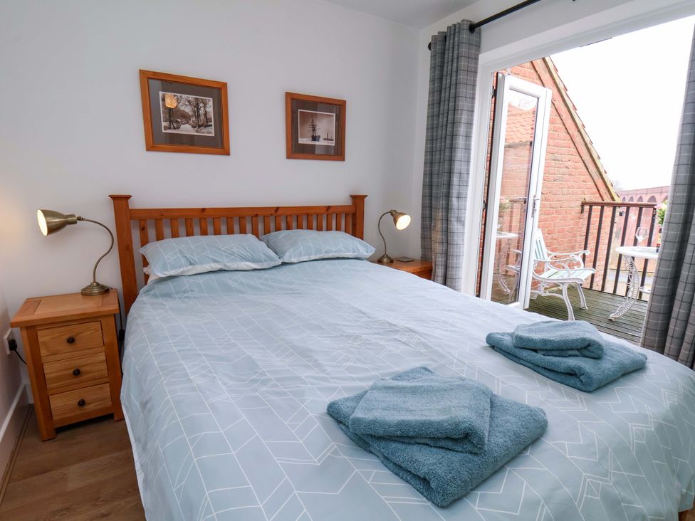 A bedroom with a bed and sliding door leading to a balcony at Berry Banks Cottage in Whitby