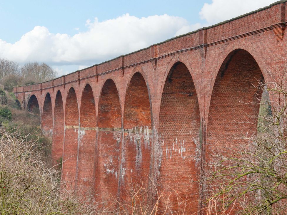 A brick viaduct with arches against a cloudy sky at an unknown location