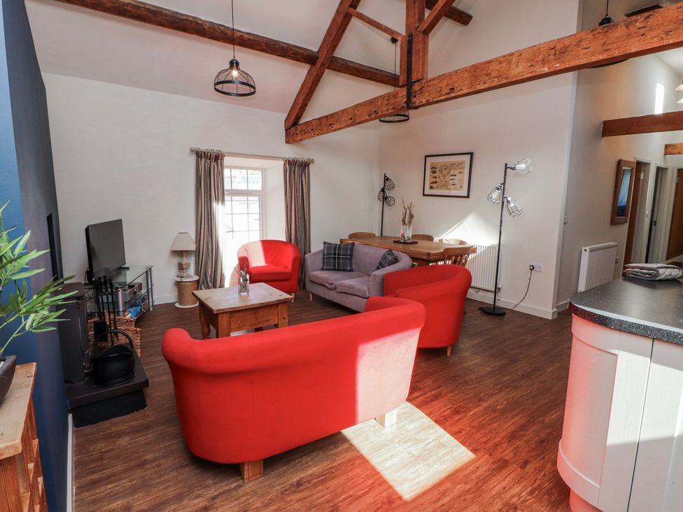 A living room with red sofas and a dining table at Hen Blas in Aberdaron
