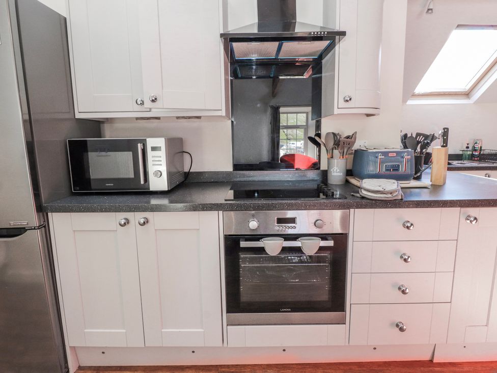 A kitchen with a microwave, oven, and utensils at Hen Blas in Aberdaron
