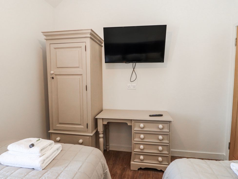 A bedroom with an armoire, desk, television, and towels at Hen Blas Aberdaron