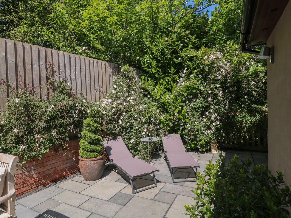 An outdoor patio with two lounge chairs a small round table potted plants and a wooden fence at Treetops in Southerton