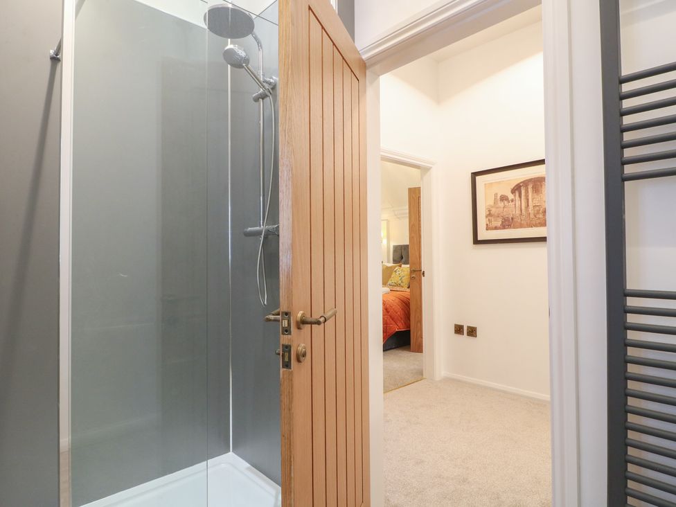 A bathroom with a shower and view of an adjacent room at Shrewsbury Lodge in Great Haywood