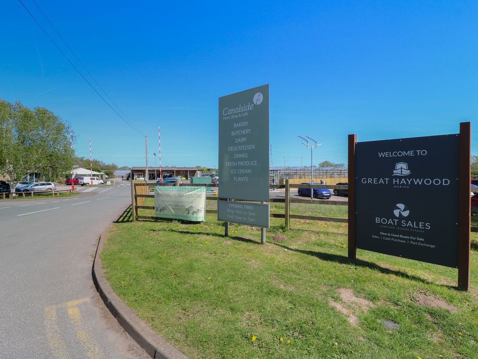 A view of the entrance to Great Haywood with signage and parked cars