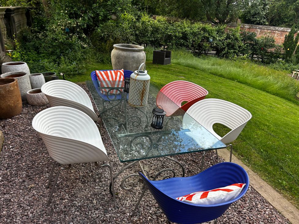 A table and chairs on gravel in a garden at Shrewsbury Lodge Ingestre near Great Haywood