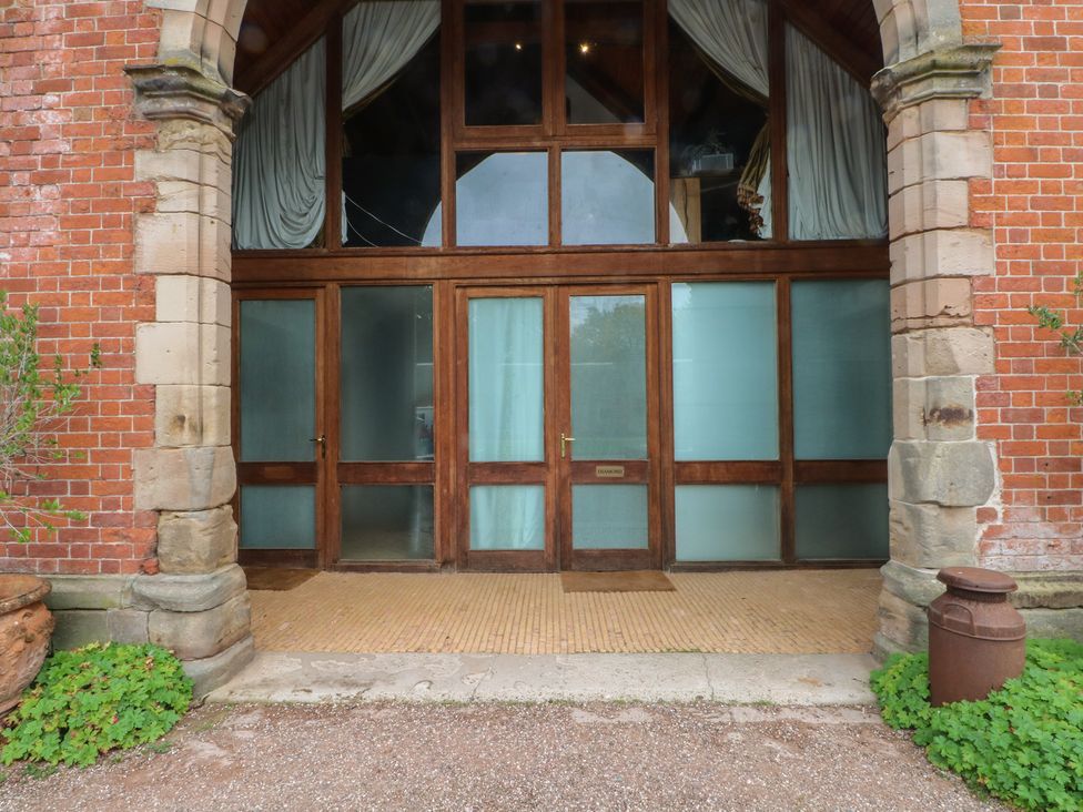 An entrance with wooden doors and a brick wall at Diamond Lodge Ingestre near Great Haywood