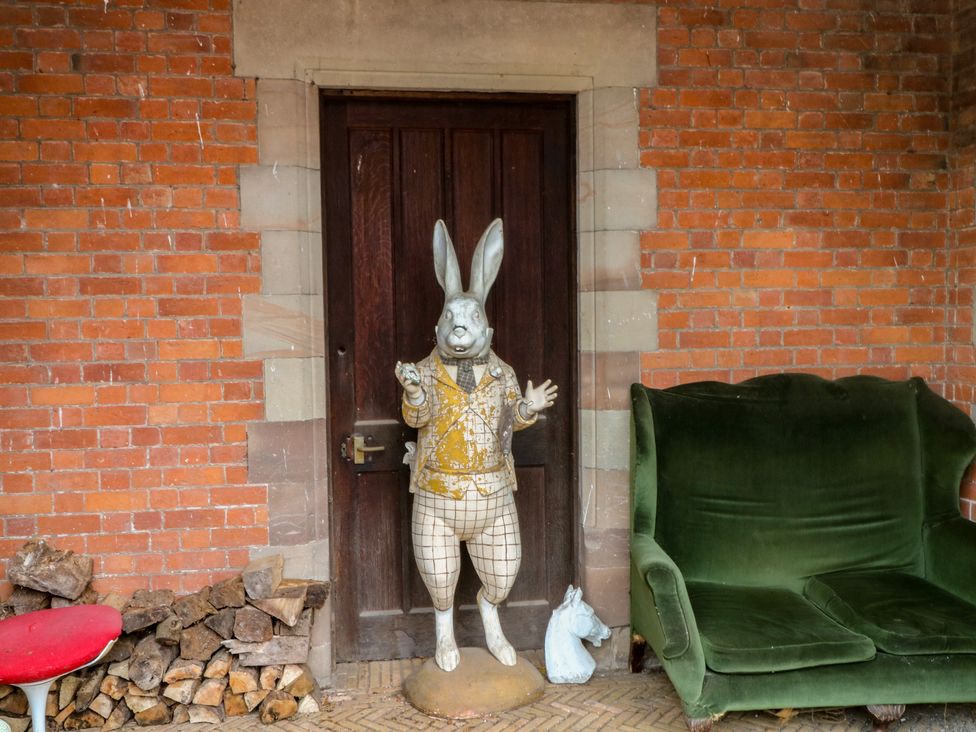 A rabbit statue and a green sofa in an outdoor area at Diamond Lodge Ingestre near Great Haywood