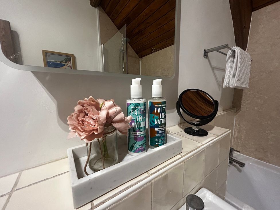 A bathroom counter with personal care products and a flower at Diamond Lodge Ingestre near Great Haywood