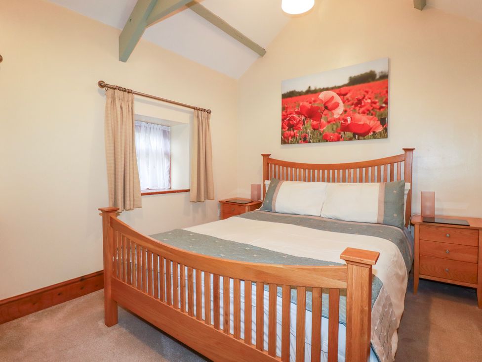 A bedroom with a bed and nightstands at Cosy Cottage in Dobwalls