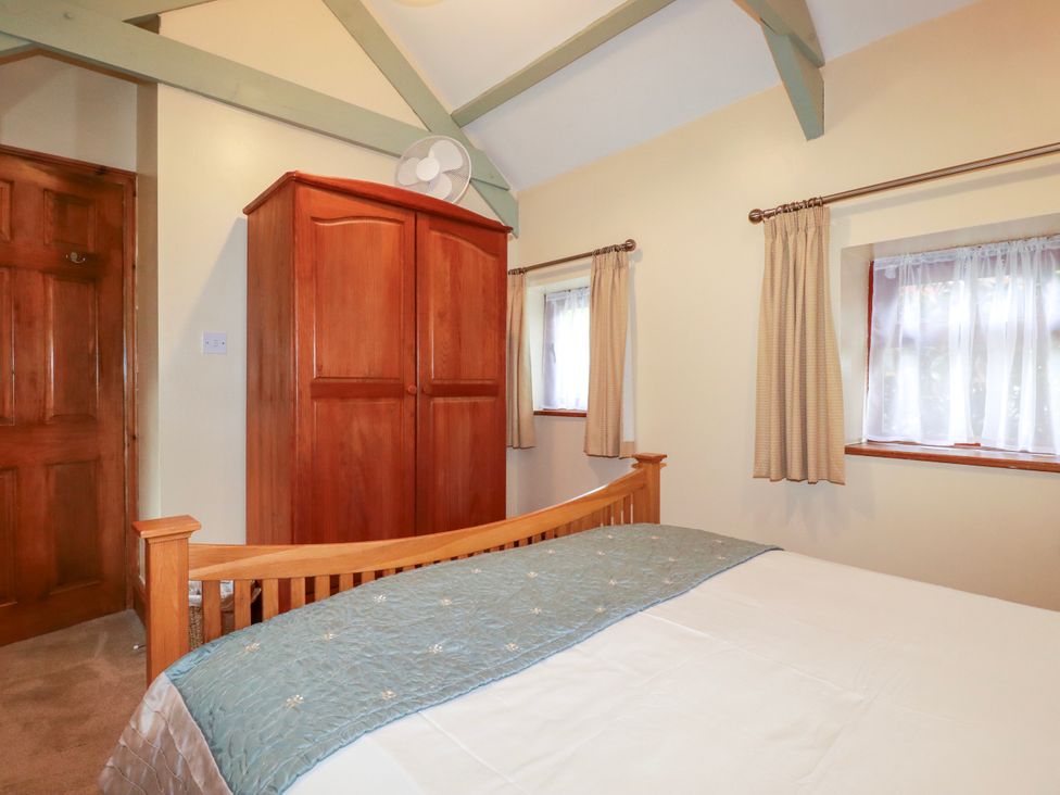 A bedroom with a bed and wardrobe at Cosy Cottage in Dobwalls