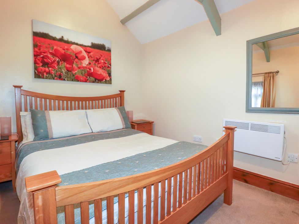 A bedroom with a bed and nightstand at Cosy Cottage in Dobwalls