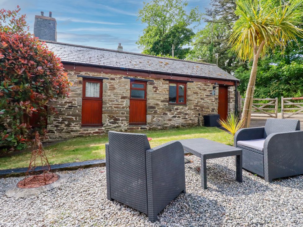 A garden with a stone cottage and outdoor seating at Cosy Cottage in Dobwalls