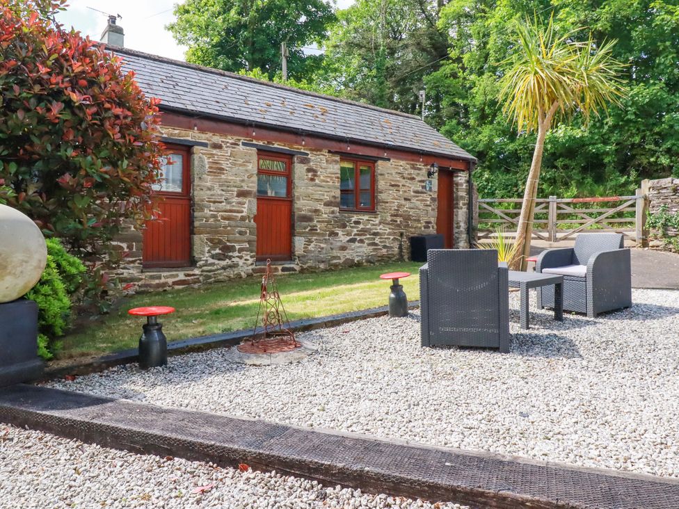 An outdoor seating area with a stone building and gravel at Cosy Cottage in Dobwalls