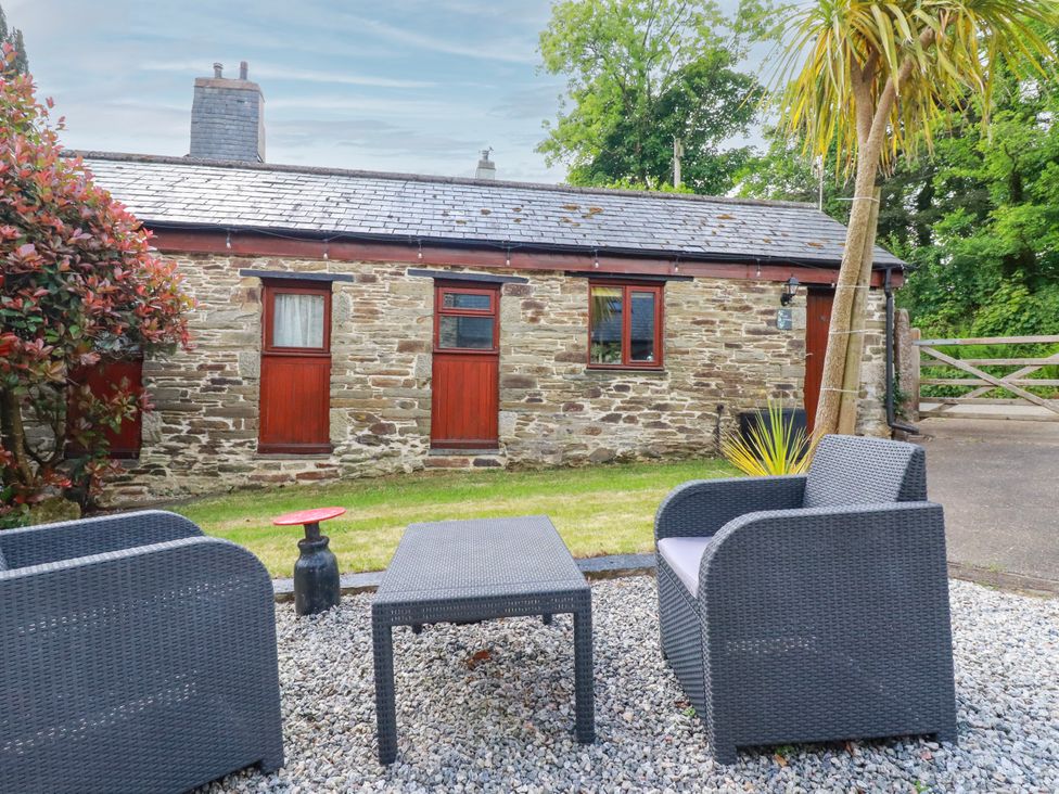 A garden with a cottage and seating area at Cosy Cottage in Dobwalls