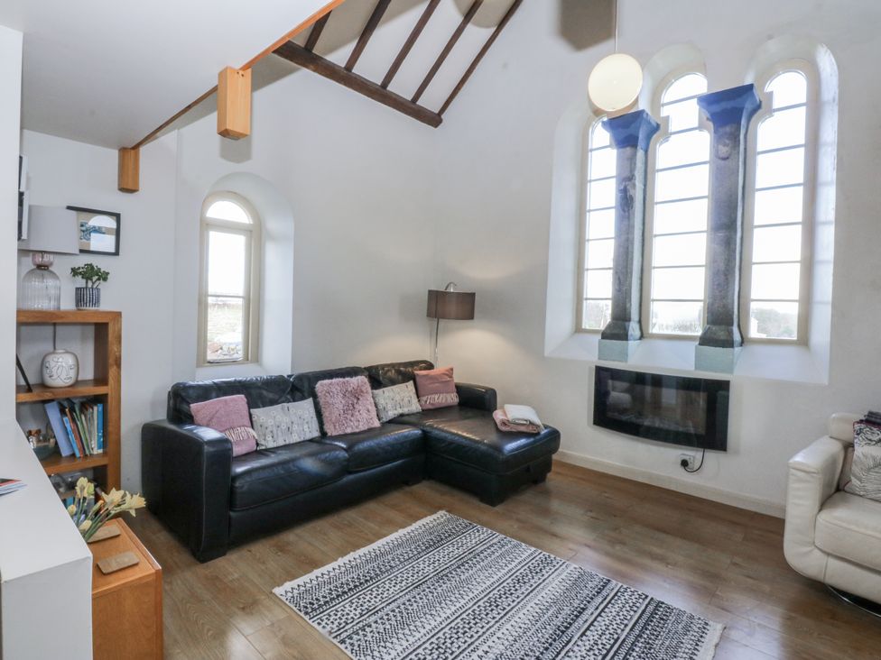 A living room with a sofa and a window at Eglwys St Cynfil in Penrhos near Pwllheli