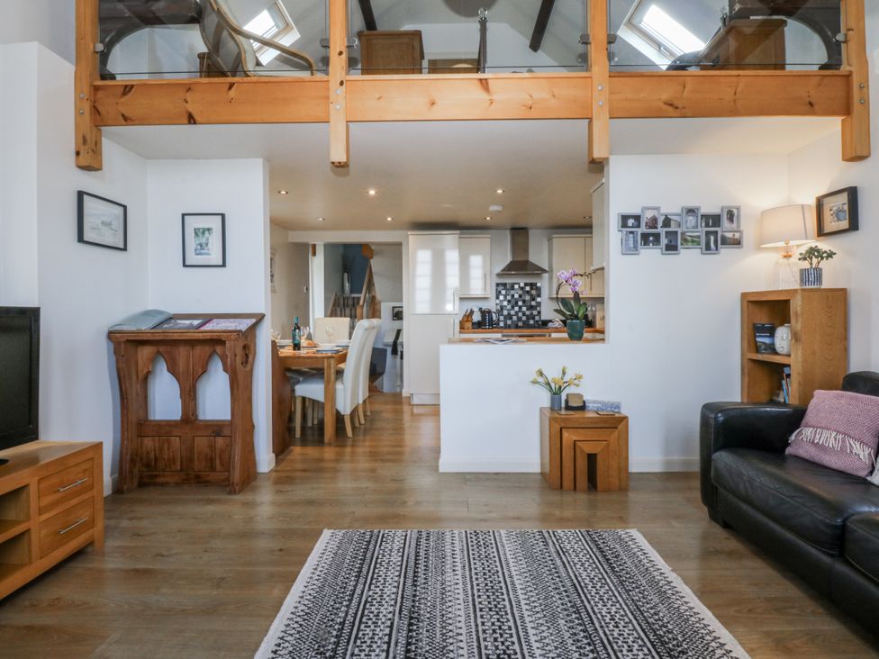 A living room with a sofa and dining area at Eglwys St Cynfil Penrhos near Pwllheli