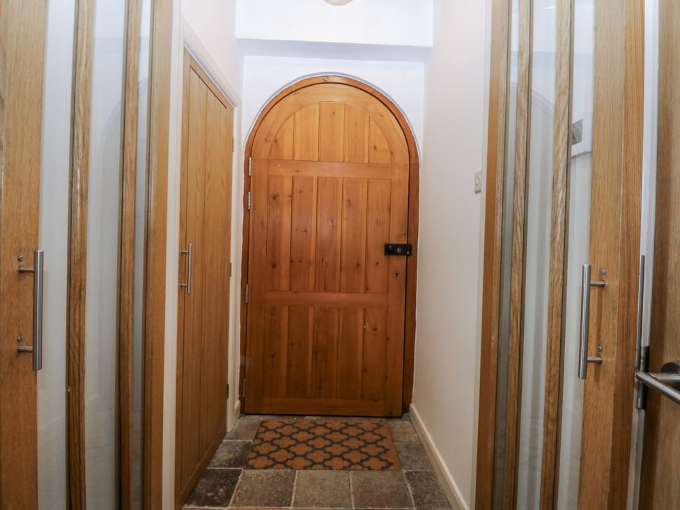A hallway with wooden doors and a door mat at Eglwys St Cynfil Penrhos near Pwllheli