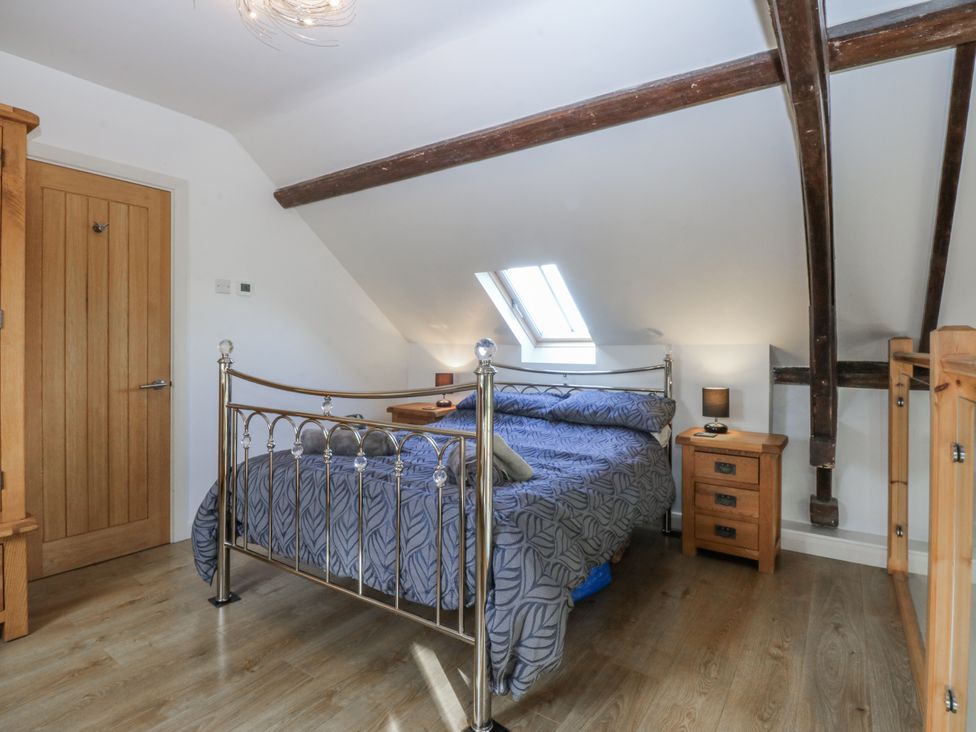 A bedroom with a bed and wooden furniture at Eglwys St Cynfil Penrhos near Pwllheli