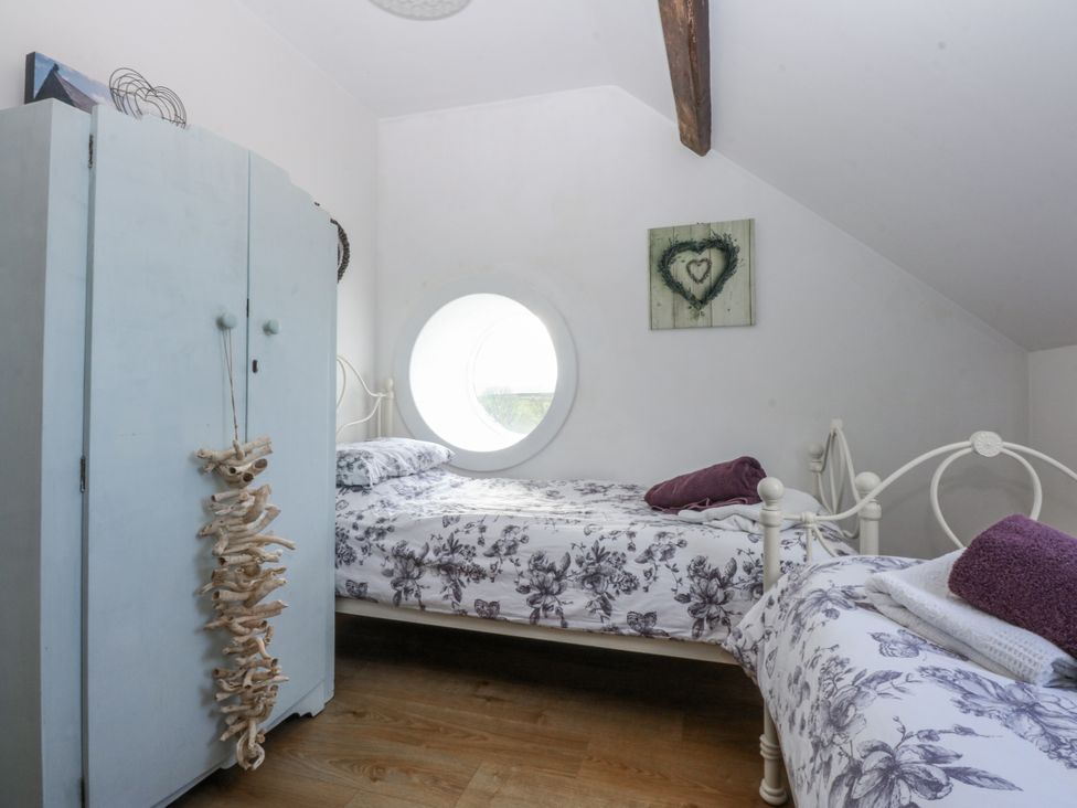 A bedroom with two beds and a wardrobe at Eglwys St Cynfil Penrhos near Pwllheli