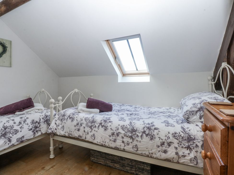 A bedroom with two beds and a window at Eglwys St Cynfil in Penrhos near Pwllheli