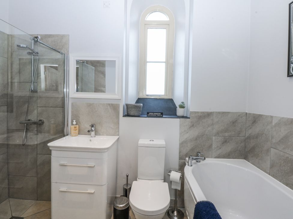 A bathroom with a shower, vanity, toilet and bathtub at Eglwys St Cynfil Penrhos near Pwllheli