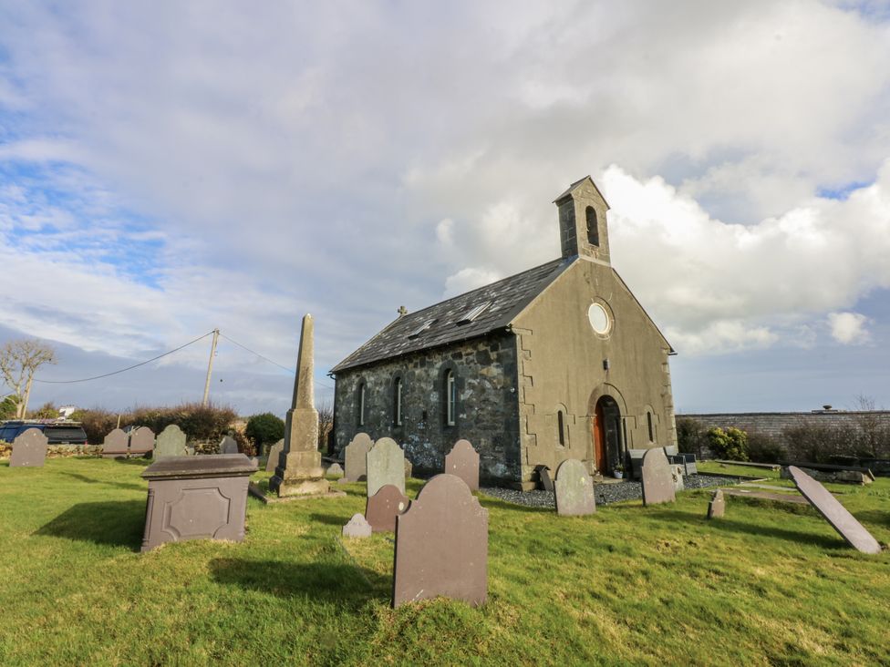 A church with gravestones in the foreground at Eglwys St Cynfil in Penrhos near Pwllheli