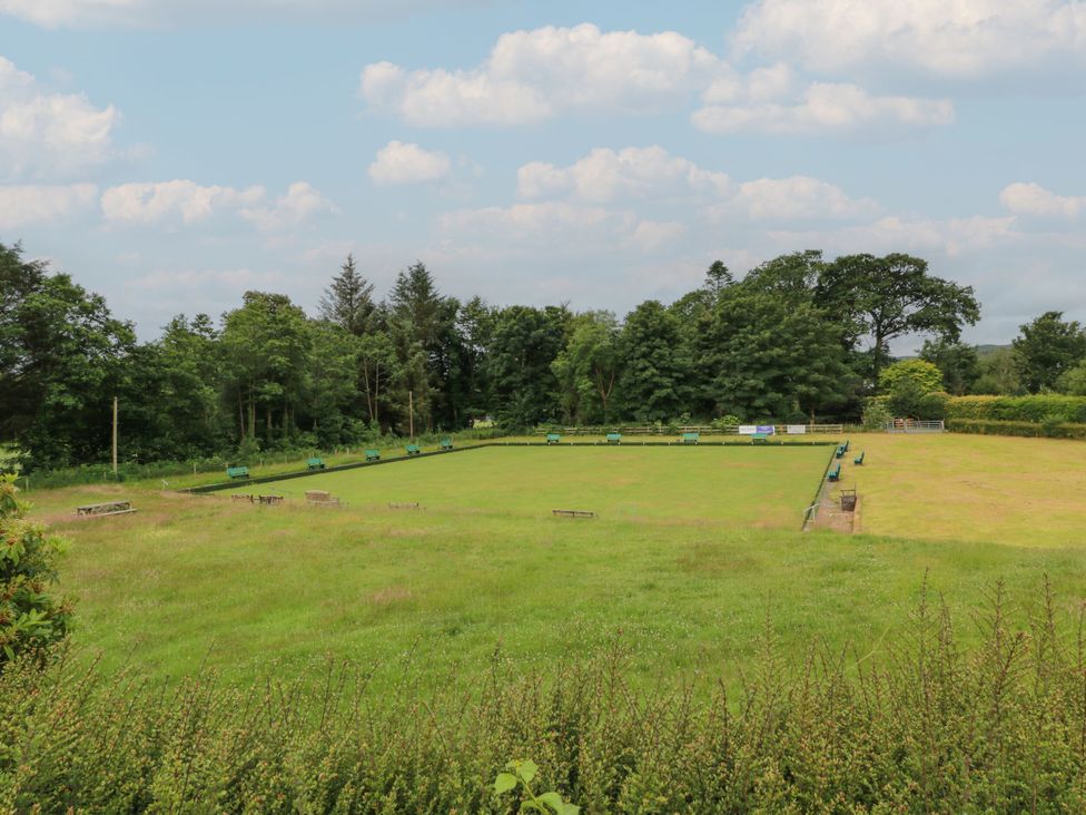 A grassy area with benches and trees at The Old Brewery Store in Gatehouse Of Fleet