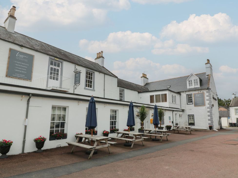 An outdoor area with tables and umbrellas at The Old Brewery Store in Gatehouse Of Fleet