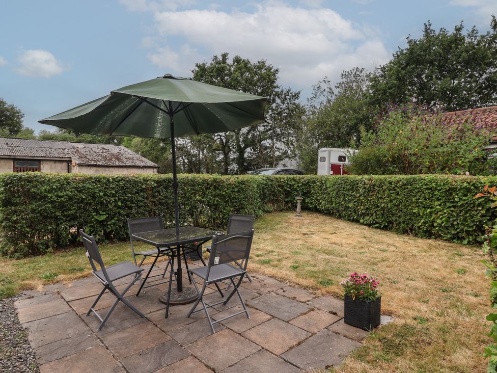 A garden with a table and chairs under an umbrella at Lillieput Lodge in Melbourne