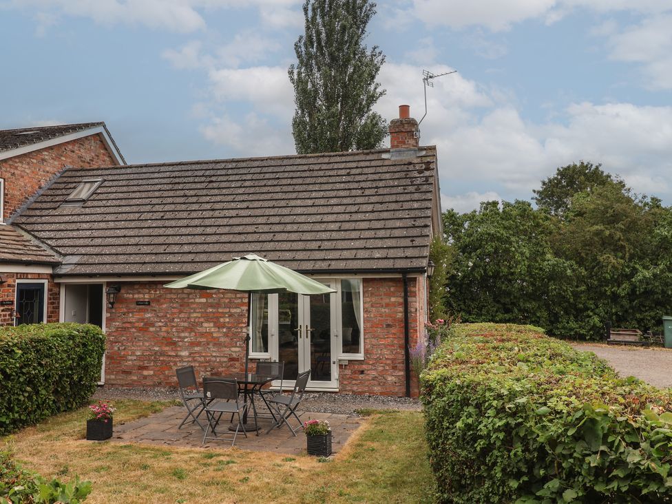 A cottage with patio seating and an umbrella at Lillieput Lodge in Melbourne