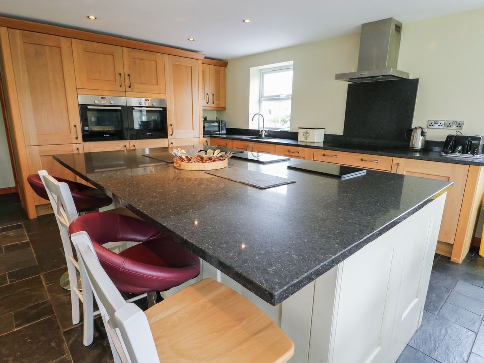 A kitchen with wooden cabinetry and a central island at Chapel House Elim near Llanddeusant