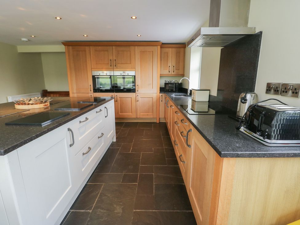 A kitchen with wooden cabinets and a central island at Chapel House Elim near Llanddeusant